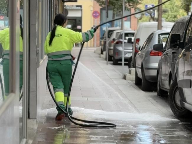 Operaria de los servicios de limpieza baldeando en aceras de Torrejón